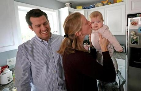 Keene, N.H., police officer Steve Tenney (right) plays with Sloan St. James, the baby who received part of his liver. At left in the child?s Bourne kitchen are her mother, Sarah, and father, Chris.
