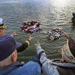 USS Constitution's 75th Commanding Officer Commander Nathaniel Shick left, and Pearl Harbor survivors Freeman K. Johnson and Emery Arsenault throw wreaths into water in Charlestown.