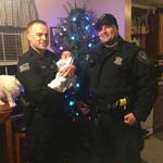 Uxbridge police officers Kyle Tripp (left) and William Ethier visited the baby they helped save last Thursday after it stopped breathing.