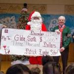 Dec. 21, 2017 - Students, teachers, staff, families and the PTA at the Patrick Lyndon Pilot School in West Roxbury donated more than $3,000 this year to Globe Santa, a program of the Boston Globe Foundation that provides Christmas gifts to 35,000 children in Eastern Massachusetts. Pictured with a banner celebrating their accomplishment at a holiday concert Thursday are (left to right) Upper School Principal Andre Ward, Globe Santa, Executive Director of Globe Santa Bill Connolly, and Lower School Principal Katie Tunney. Photo Credit: Justin Saglio for the Boston Globe. Section: Globe Santa.