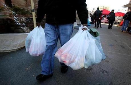 BOSTON, MA- DECEMBER 16, 2017: A customer uses plastic bags while shopping at the Haymarket in Boston, MA on on December 16, 2017. Mayor Martin J. Walsh has until Monday to make a decision on the single-use plastic bag ban that unanimously passed the City Council last month. (CRAIG F. WALKER/GLOBE STAFF) section: metro reporter:
