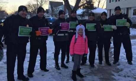 Quincy officers held signs for Bridget Kelley (front) as she returned to school Tuesday. 
