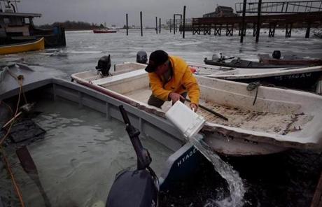 SNOW SLIDER2 SCITUATE, MA- JANUARY 04, 2018: A fisherman bails water from a flooded boat in Scituate Harbor during during the storm in Scituate, MA on January 04, 2018. Massachusetts is bracing for a fast and furious norÕeaster that is expected to lash the state Thursday with high winds, dump more than a foot of snow on some areas, and cause flooding in coastal communities, before sweeping out of the area late in the day. The National Weather Service said the storm would pack the bulk of its precipitation into a relatively narrow time window Ñ approximately from 10 a.m. to 4 p.m. Some communities could get 18 inches of snow or more before the system fades. (CRAIG F. WALKER/GLOBE STAFF) section: metro reporter:
