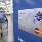 FILE - In this Thursday, June 4, 2015, file photo, a customer walks past a sign promoting the Sam's Club Mastercard credit card at a Sam's Club store store in Bentonville, Ark. Saving money on holiday purchases now by opening a store credit card could cost you later in credit score points. (AP Photo/Danny Johnston, File)