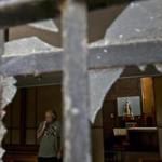 A church employee surveys the damage caused by an overnight fire bomb attack at the Emmanuel Catholic Church, in Santiago, Chile, Friday, Jan. 12, 2018. Three churches were attacked with fire bombs in Santiago overnight, dropping leaflets at the scene against the upcoming visit of Pope Francis, and calling for a 