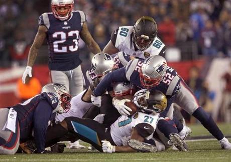 Foxborough, MA 1/21/2018 - New England Patriots outside linebacker Elandon Roberts (52) and New England Patriots defensive end Lawrence Guy (93) wrap up Jacksonville Jaguars running back Leonard Fournette (27). The New England Patriots host the Jacksonville Jaguars in an NFL AFC championship game at Gillette Stadium in Foxborough, Mass., Jan. 21, 2018.(Barry Chin/Globe Staff) 
