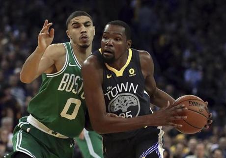 Golden State Warriors' Kevin Durant, right, drives the ball against Boston Celtics' Jayson Tatum (0) during the first half of an NBA basketball game Saturday, Jan. 27, 2018, in Oakland, Calif. (AP Photo/Ben Margot)
