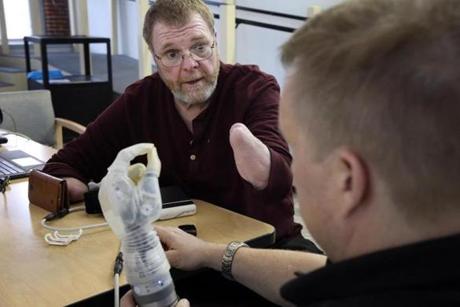 (STORY EMBARGOED UNTIL FEB 22) Boston, MA- February 13, 2018: Air Force veteran Ron Currier, 63, left, talks about his LUKE Arm with support engineer Joe Sullivan, of Mobius Bionics at Next Step Bionics and Prosthetics, Inc. in Manchester, NH on February 13, 2018. Air Force veteran Ron Currier, 63, lost both arms in a high voltage accident when he was 20 years old. He is now being fitted with a second LUKE (Life Under Kinetic Evolution) Arm. His current LUKE Arm, his left, is controlled with Inertial Measurement Units (IMUs) that are worn on the shoes. He is now being fitted for a second arm, his right, that will be controlled by electrodes attached to his arm and patterns recognition software. (Craig F. Walker/Globe Staff) section: metro reporter: 
