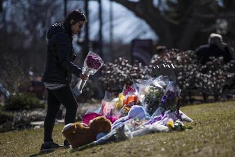 Winchester, MA - 2/27/2018 - A woman lays flowers on a makeshift memorial for Deane Kenny Stryker, a woman fatally stabbed in one of the Winchester Public Library's reading rooms, on the library's lawn in Winchester, MA, Feb. 27, 2018. The library had been closed since the stabbing over the weekend. (Keith Bedford/Globe Staff)
