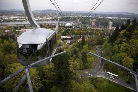 In this Wednesday, April 24, 2013 photo, a sky tram gives a spectacular view of downtown and the forested West Hills in Portland, Ore. One of the latest Portland efforts is something called the 4T trail, a tour that incorporates the city's light-rail trains, trolleys, forest trails and even a sky tram that gives spectacular views of downtown and the surrounding countryside from the West Hills. (AP Photo/Don Ryan)
