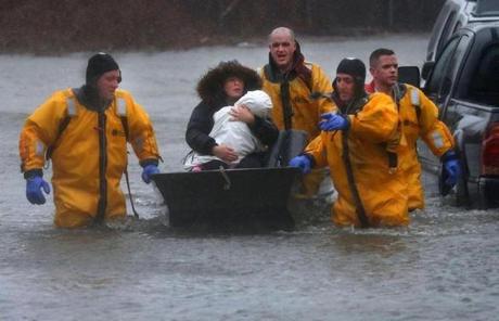 A mother and child are rescued by a boat from their home in Quincy.
