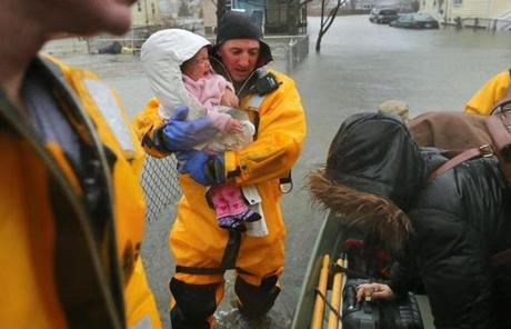 STORM SLIDER Quincy-03/02/18- A rescue worker holds a crying baby rescued with her mother from a flooded home on Post Island Road. Many water rescue evacuations took place at residences flooded on Post Island Road in the Houghs Neck section of Quincy. Quincy firefighters used beats and front end loaders to rescue many residents. John Tlumacki/Globe Staff(metro)
