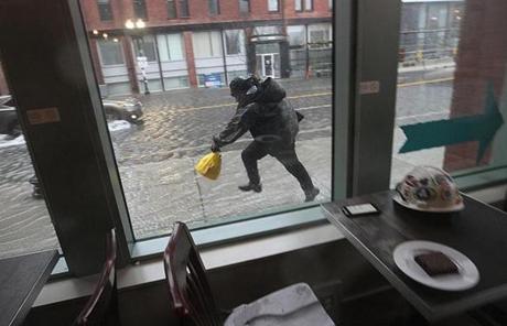 A person dashed through the rising water as seen from inside a dry coffee shop.
