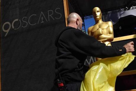 A worker takes away the plastic cover of a statue on the red carpet a few hours before the 