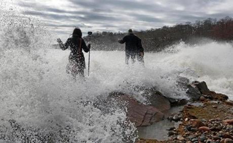 Gloucester, MA 3/4/2018: Massachusetts Governor Charlie Baker (right) came to Gloucester today to inspect some of the areas that were affected by the weekend storm. He is pictured getting soaked by a wave while walking on a sea wall at Stage Fort Park with State Senator Bruce Tarr (R-Gloucester) (to his right). Salem News reporter Mary Markos (left) is getting hit by the same wave while shooting video, and she is about to fall into the water herself (next photo). (Jim Davis/Globe Staff)
