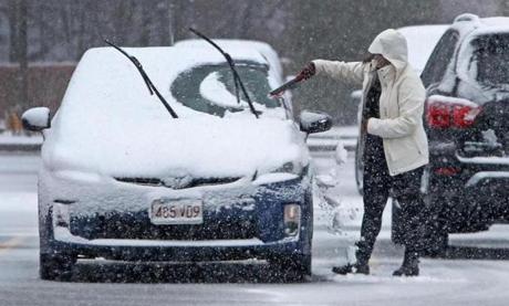 A motorist cleaned snow off of their car in tha parking lot of a shopping plaza near downtown Fitchburg Wednesday.

