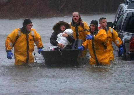 Quincy-03/02/18-A mother and child are rescued by a boat from their home. Many water rescue evacuations took place at residences flooded onPost Island Road in the Houghs Neck section of Quincy. Quincy firefighters used boats and front end loaders to rescue many residents. John Tlumacki/Globe Staff(metro)

