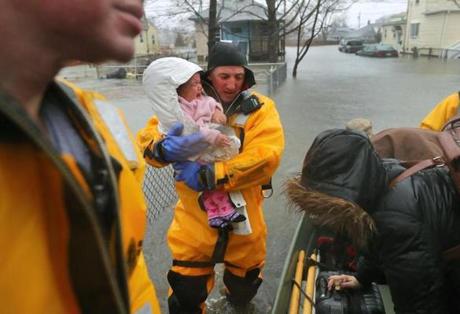Quincy-03/02/18- A rescue worker holds a crying baby rescued with her mother from a flooded home on Post Island Road. Many water rescue evacuations took place at residences flooded on Post Island Road in the Houghs Neck section of Quincy. Quincy firefighters used beats and front end loaders to rescue many residents. John Tlumacki/Globe Staff(metro)
