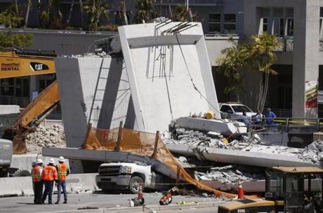 Workers stood next to a section of a collapsed pedestrian bridge Friday near Florida International University in the Miami area.
