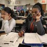 Dailene Barros used glasses she borrowed from Joceline Alexandra Oliveira (left) in an eighth-grade science class at North Middle School in Brockton. 