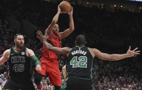 Portland Trail Blazers guard CJ McCollum passes the ball over Boston Celtics forward Al Horford, right, as center Aron Baynes, left, closes in during the first half of an NBA basketball game in Portland, Ore., Friday, March 23, 2018. (AP Photo/Steve Dykes)
