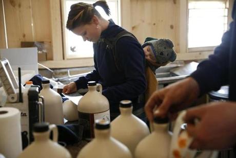 Abby Roleau carried her 5-month-old son, Bradley, on her back as she and Trent Roleau put labels onto their maple syrup. 
