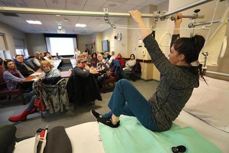 At New England Baptist Hospital, physical therapist Caitlin Abusamra demonstrated getting out of bed for a class of patients about to undergo joint replacement surgery. 
