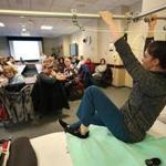 At New England Baptist Hospital, physical therapist Caitlin Abusamra demonstrated getting out of bed for a class of patients about to undergo joint replacement surgery. 