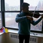 In this March 28, 2018 photo, Venezuelan musician Wuilly Arteaga plays his violin inside a small apartment provided by a benefactor, in New York. The musician has gone from dodging police and tear gas in Caracas to entertaining New York City commuters with his violin. (AP Photo/Bebeto Matthews)