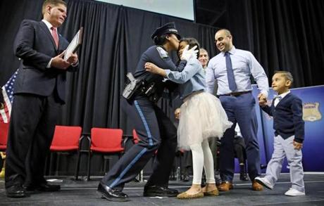 Officer Jennifer de los Santos (center) kissed her daughter Nya, 8, and was joined by her husband, Jason, and their son Jace, 4, after receiving her police badge Tuesday.
