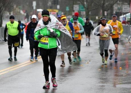 Back of the pack runners use a variety of ways to cover up against the rain as they climb Heartbreak Hill in Newton during the 2015 Boston Marathon. This Monday?s Marathon is expected to be another rainy day.
