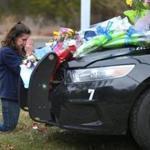 Jeanette Smith from Harwich knelt and prayed in front of the cruiser belonging to slain Yarmouth k-9 officer Sean Gannon which is adorned with flowers parked in front of the police station.