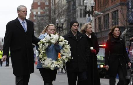 Boston, MA--4/15/2018-- Governor Charlie Baker (L) escorts Patricia Campbell, mother of Krystle Campbell, as she carries a wreath in honor of her late daughter and the others killed in the 2013 marathon bombing on the five year anniversary of the Boston Marathon bombing. (Jessica Rinaldi/Globe Staff) Topic: 16marathoncolor Reporter:
