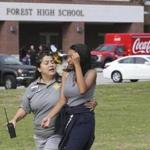 A student is comforted by a school official outside Forest High School. 