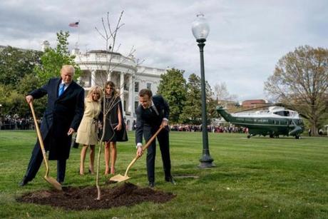 FILE- In this April 23, 2018, file photo, first lady Melania Trump, second from right, and Brigitte Macron, second from left, watch as President Donald Trump and French President Emmanuel Macron participate in a tree planting ceremony on the South Lawn of the White House in Washington. The sapling, a gift from Macron on the occasion of his state visit, is gone from the lawn. A pale patch of grass was left in its place. The White House hasn't offered an explanation. (AP Photo/Andrew Harnik, File)
