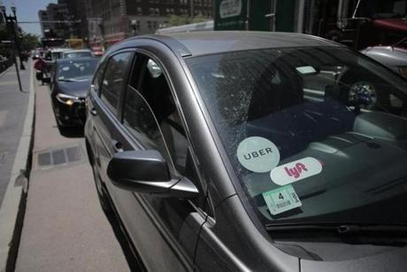 A vehicle with placards for both Lyft and Uber waited at a traffic light outside South Station. Boston accounted for more than half of the 65 million rides Uber and Lyft provided across all of Massachusetts last year, a new report said.
