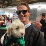 Northeastern graduate Jake Heney holds a puppy at the opening ceremonies for The Patios on Boston City Hall Plaza.