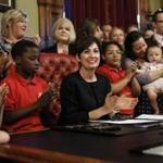 Iowa Gov. Kim Reynolds, center, reacts after signing a six-week abortion ban bill into law during a ceremony in her formal office, Friday, May 4, 2018, in Des Moines, Iowa. The bill gives Iowa the strictest abortion restrictions in the nation, setting the state up for a lengthy court challenge. (AP Photo/Charlie Neibergall)