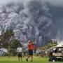 Two men played golf as an ash plume rose in the distance from the Kilauea volcano on Hawaii's Big Island on Tuesday.