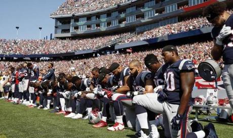 FILE - In this Sept. 24, 2017 file photo, several New England Patriots players kneel during the national anthem before an NFL football game against the Houston Texans in Foxborough, Mass. Patriots fans have burned team gear in protest after a number of players kneeled during the national anthem before last weekend's game. More than 100 people came out to Swansea, Massachusetts, on Thursday, Sept. 28 to throw Patriots T-shirts and other team apparel into a fire pit as they waved American flags and sang patriotic songs. (AP Photo/Michael Dwyer, File)
