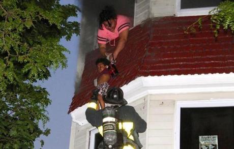 A woman handed her child to Boston firefighter Patrick Callahan as he rescued them from the third story of a burning house in Roxbury on Thursday.
