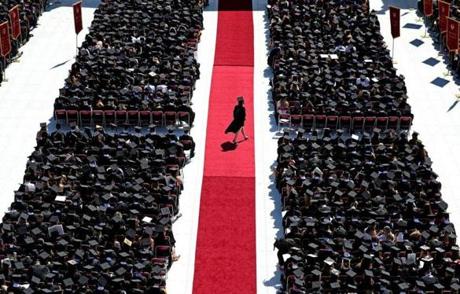 A lone participant walks the red carpet during the Boston College commencement at Alumni Stadium.
