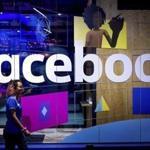 FILE - In this Tuesday, April 18, 2017, file photo, a conference worker passes a demo booth at Facebook's annual F8 developer conference, in San Jose, Calif. Facebook says it is changing how it identifies 