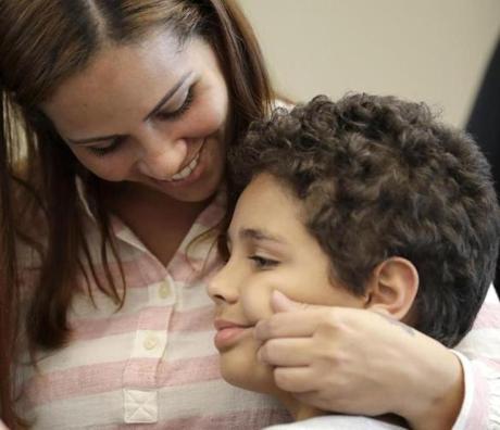 Lidia Karine Souza smiles and pinches the cheek of her son Diogo at the Mayer Brown law firm during a news conference shortly after Diogo was reunited with his mother Thursday, June 28, 2018, in Chicago. Federal judge Manish Shah earlier today ordered the immediate release from detention of the 9-year-old Diogo who was separated from his mother at the U.S.-Mexico border in May. (AP Photo/Charles Rex Arbogast)
