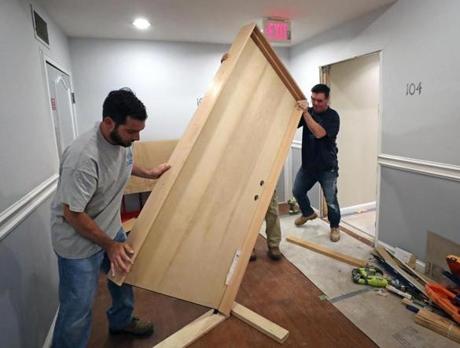 Workers helped Andrew Hassey lift a soundproof door into place at his North End condo.
