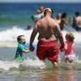 David Caillouette wades in the ocean with his twins, Aidan (left) and Madeline, 5, in Orleans.