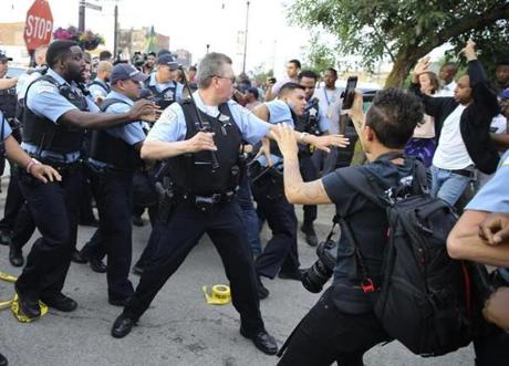Members of the Chicago police department scuffle with an angry crowd at the scene of a police involved shooting in Chicago on Saturday.
