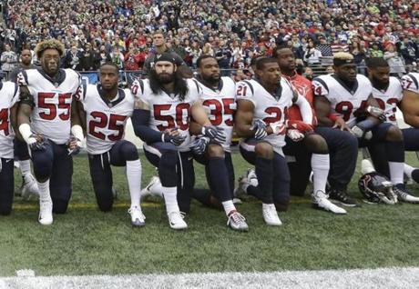 FILE - In this Oct. 29, 2017, file photo, Houston Texans players kneel and stand during the singing of the national anthem before an NFL football game against the Seattle Seahawks, in Seattle. NFL owners have approved a new policy aimed at addressing the firestorm over national anthem protests, permitting players to stay in the locker room during the 