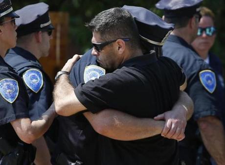 A police officer was embraced during a procession held outside of the Boston medical examiner's office after a Weymouth officer was killed in the line of duty. 
