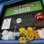 Flowers left by mourners rest on the ticket counter at the closed Ride the Ducks attraction Saturday in Branson, Mo.